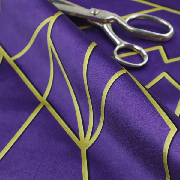 A close-up of a luxurious deep purple or violet fabric featuring a fractured, geometric mosaic pattern. The dark, matte background is segmented by a network of recessed metallic gold lines that form sharp, irregular polygons. This "shattered-glass" effect creates a dramatic visual contrast, blending the rich, royal tones of the textile with shimmering, Art Deco-inspired gold accents for a bold and sophisticated look.
