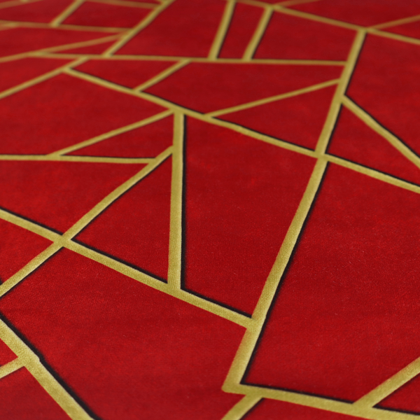 A close-up of a luxurious vibrant red fabric featuring a fractured, geometric mosaic pattern. The rich, matte background is segmented by a network of recessed metallic gold lines that form sharp, irregular polygons. This "shattered-glass" or "cracked ice" effect creates a striking visual contrast, blending the intense red base with shimmering, Art Deco-inspired gold linework for a dramatic and architectural look.