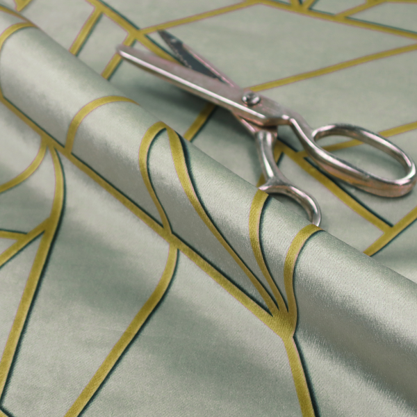 A close-up of a luxurious silver fabric featuring a fractured, geometric mosaic pattern. The soft, matte background is segmented by a network of recessed metallic gold lines that form sharp, irregular polygons. This "shattered-glass" effect creates a calm yet architectural look, blending cool, desaturated tones with shimmering, Art Deco-inspired gold linework for a high-end, contemporary finish.