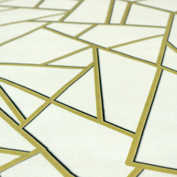 A close-up of a luxurious stark white or ivory fabric featuring a fractured, geometric mosaic pattern. The clean, matte background is segmented by a network of recessed metallic gold lines that form sharp, irregular polygons. This "shattered-glass" effect creates a sophisticated architectural look, pairing a bright, neutral base with shimmering, Art Deco-inspired gold linework for a high-contrast and contemporary finish.