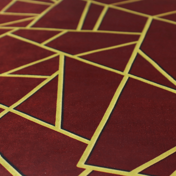 A close-up of a luxurious burgundy or wine red fabric featuring a fractured, geometric mosaic pattern. The dark, velvety matte background is segmented by a network of recessed metallic gold lines that form sharp, irregular polygons. This "shattered-glass" effect pairs a rich, deep-toned base with shimmering, Art Deco-inspired gold linework for a dramatic and architectural look.