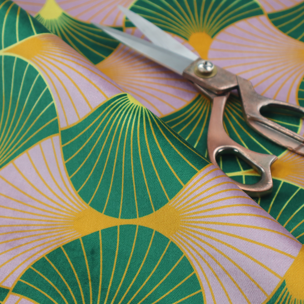 The DP-395-1 fabric features an elegant and playful Art Deco aesthetic, characterized by its interlocking scalloped fan motif and a unique, soft colour palette.