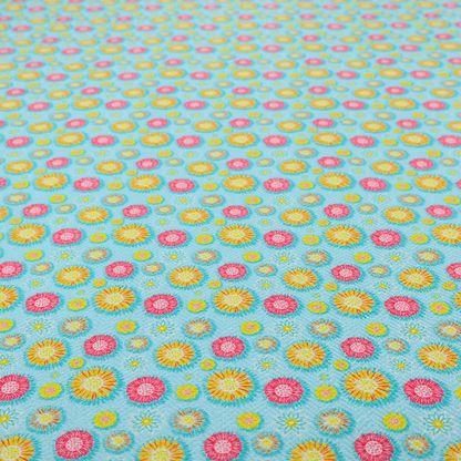 Light blue fabric featuring an all-over repeating pattern of vibrant pink and gold floral motifs interspersed with small yellow dotted accents.