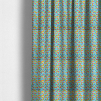 The fabric used to create these made-to-measure curtains is a light blue fabric featuring an all-over repeating pattern of vibrant pink and gold floral motifs interspersed with small yellow dotted accents.
