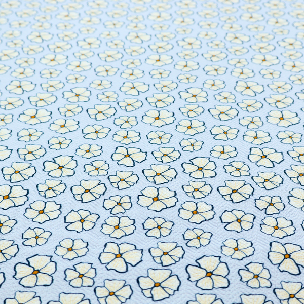 A light blue fabric featuring a dense, repeating pattern of small white flowers with yellow centres and dark outlines.