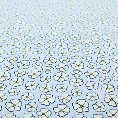 A light blue fabric featuring a dense, repeating pattern of small white flowers with yellow centres and dark outlines.