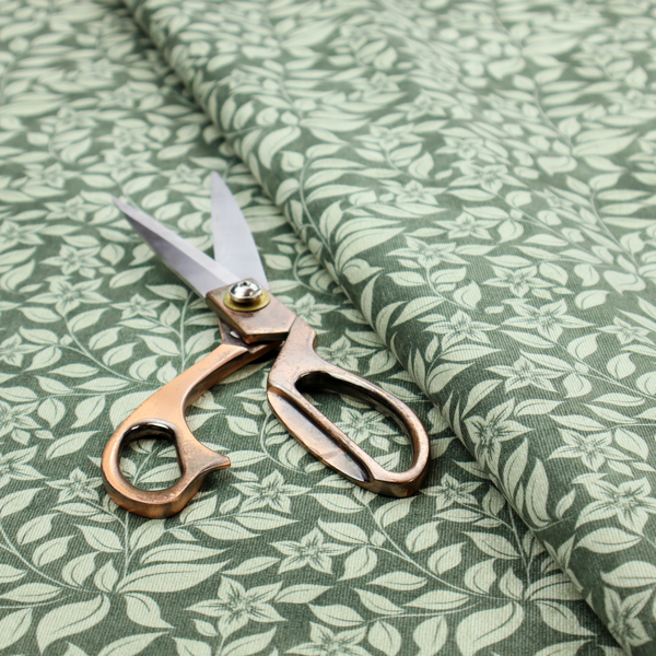 A green fabric featuring an intricate, repeating botanical pattern of trailing vines, leaves, and small white flowers.