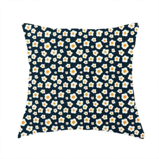 The fabric used to create this handmade cushion is a dark navy blue fabric featuring a dense, repeating pattern of small fried egg motifs with white whites and yellow yolks.