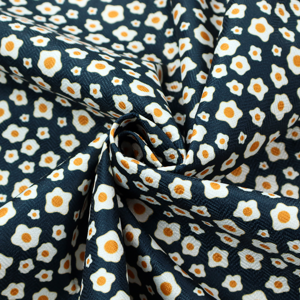 A dark navy blue fabric featuring a dense, repeating pattern of small fried egg motifs with white whites and yellow yolks.