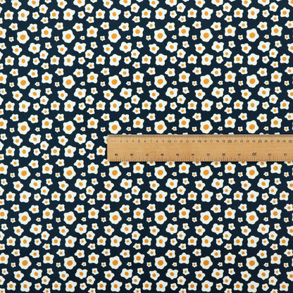 A dark navy blue fabric featuring a dense, repeating pattern of small fried egg motifs with white whites and yellow yolks.