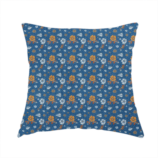 The fabric used to create this handmade cushion is a royal blue fabric featuring a detailed, repeating pattern of orange and white flowers, small leaves, and sprigs