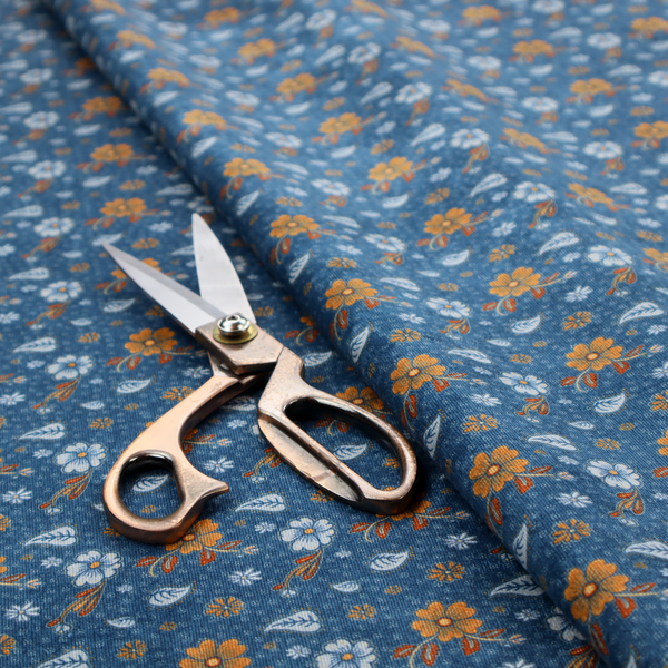 A royal blue fabric featuring a detailed, repeating pattern of orange and white flowers, small leaves, and sprigs