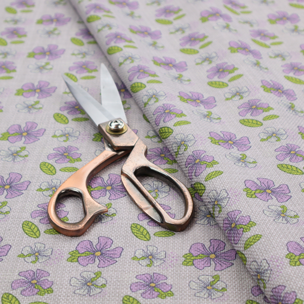 A light grey-purple fabric featuring a repeating pattern of purple and white flowers with green leaves.