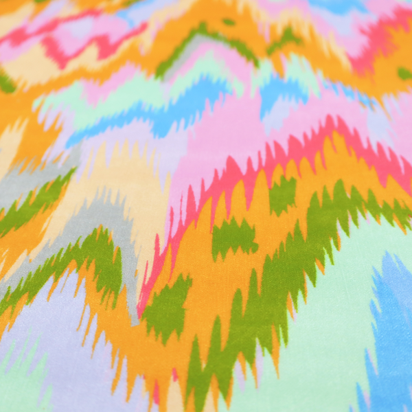 This fabric features a vibrant, multi-coloured ikat-style pattern with a soft, blurred aesthetic.