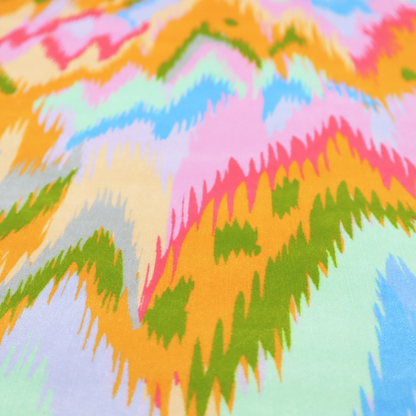 This fabric features a vibrant, multi-coloured ikat-style pattern with a soft, blurred aesthetic.