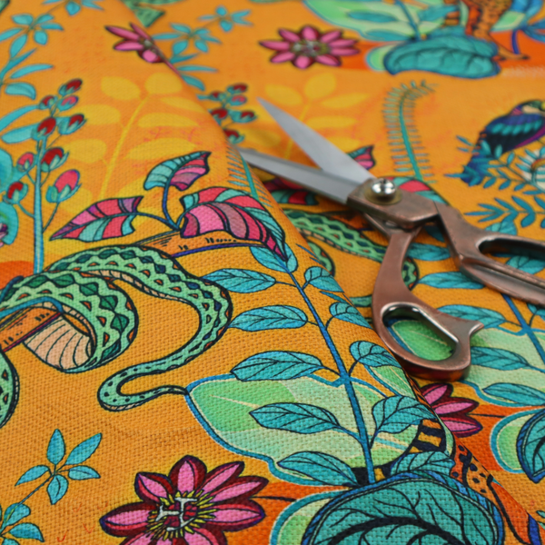 This vibrant, maximalist fabric features a stylized jungle motif set against a bold, warm orange background.