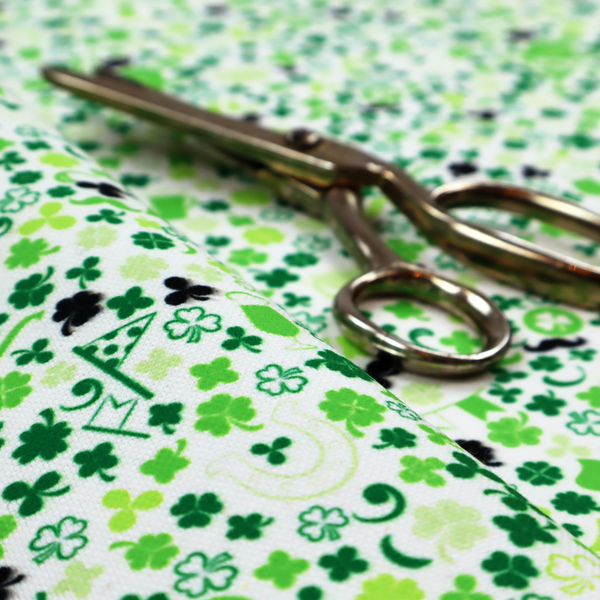 Seamless St. Patrick’s Day fabric pattern on a white background featuring green party bunting banners, frothy beer mugs, leprechaun hats with sunglasses, pipes, horseshoes, and black and green shamrocks.