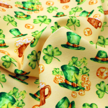 Seamless St. Patrick’s Day fabric pattern on a warm buttercream yellow background. Features watercolour-style green leprechaun top hats, wooden beer steins with foam, overflowing gold coins, and bright green shamrocks.