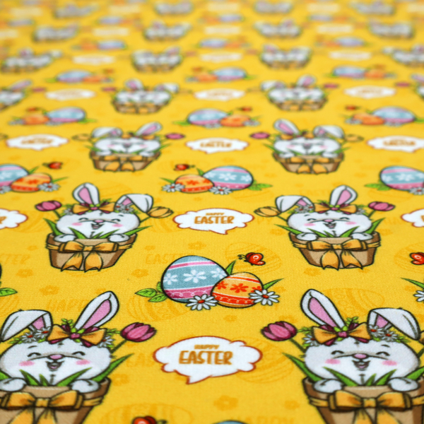This is a vibrant, repetitive Easter-themed pattern fabric, set against a bright mustard-yellow background. The design features several recurring hand-drawn, cartoon-style illustrations.