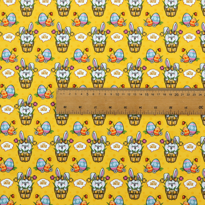 This is a vibrant, repetitive Easter-themed pattern fabric, set against a bright mustard-yellow background. The design features several recurring hand-drawn, cartoon-style illustrations.