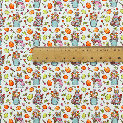 This fabric features a playful and detailed Easter garden pattern set against a crisp, white background. The design is a bright and busy "tossed" print that combines the popular gnome trend with traditional spring motifs.