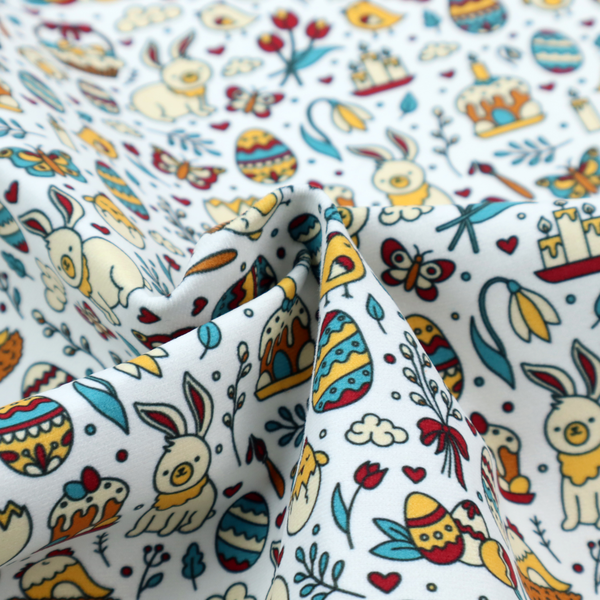 This fabric features a whimsical, hand-drawn Easter doodle pattern set against a clean, pale blue-grey background. The design is a dense, "scatter" style print using a primary colour palette of deep red, mustard yellow, and teal blue.