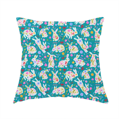 The fabric used to create these handmade cushions features a vibrant, folk-art inspired Easter pattern set against a rich teal-green background. The design is characterized by its high-contrast colour palette and intricate floral silhouettes.