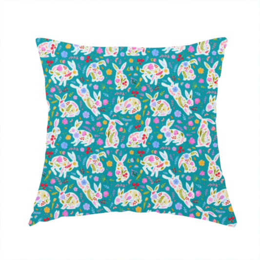 The fabric used to create these handmade cushions features a vibrant, folk-art inspired Easter pattern set against a rich teal-green background. The design is characterized by its high-contrast colour palette and intricate floral silhouettes.