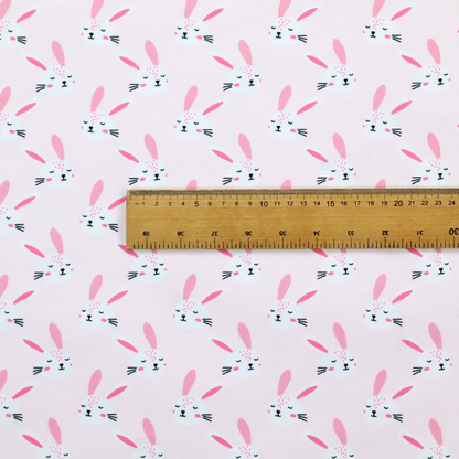 This fabric features a modern, minimalist bunny pattern set against a soft, pale pink background. The design is clean and contemporary, focusing on a repeating motif of stylized rabbit faces.