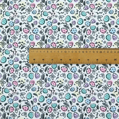 This fabric features an artistic, hand-illustrated Easter egg pattern on a cool, pale blue background. The design has a sketchbook or "doodle" quality, with expressive black ink outlines and soft watercolour-style colour accents.