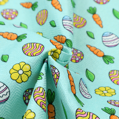 This fabric features a bright and cheerful Easter garden pattern set against a refreshing sky-blue background. The design is clean and energetic, using a cartoon-style illustration technique with bold black outlines.