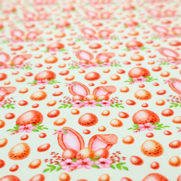 This fabric features a warm, watercolour-style Easter pattern on a very pale mint-green background. The design is rich in texture and soft tones, giving it a cosy and traditional holiday feel.