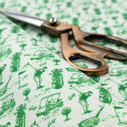 A repeating novelty fabric pattern featuring green hand-sketched illustrations of golfers, golf bags, golf carts, and flags on a light cream-colored background.