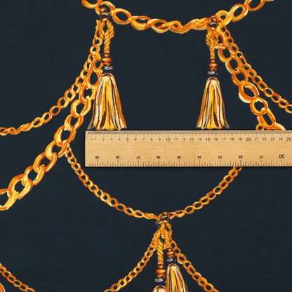 A luxury fashion-inspired fabric on a deep navy-black background. The design features elegant, draped golden chains arranged in a repeating scallop or 'swag' pattern, accented by highly detailed golden silk tassels suspended from ornate beaded cords.