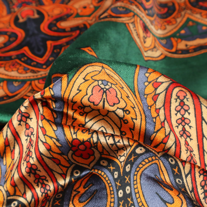 Ornate jewel-toned border print fabric with a central green stripe flanked by intricate Persian-inspired teardrop and medallion motifs in amber and navy.