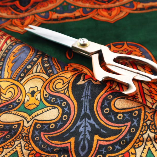 Ornate jewel-toned border print fabric with a central green stripe flanked by intricate Persian-inspired teardrop and medallion motifs in amber and navy.