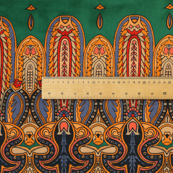 Ornate jewel-toned border print fabric with a central green stripe flanked by intricate Persian-inspired teardrop and medallion motifs in amber and navy.