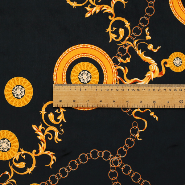 A luxury baroque-style fabric on a black ground featuring a trellis of golden chains interspersed with ornate sun-medallions and amber floral scrolls.