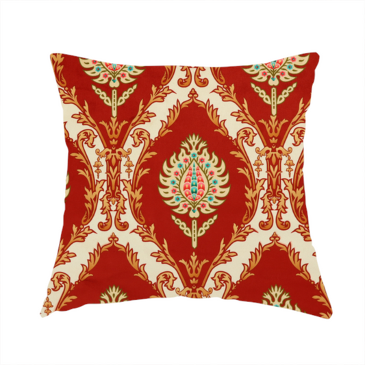 The fabric used to create these handmade cushions is a grand, symmetrical damask-style fabric on a rich crimson red ground featuring ornate cream-colored leaf frames enclosing vibrant, stylized floral pinecones with teal and pink accents.