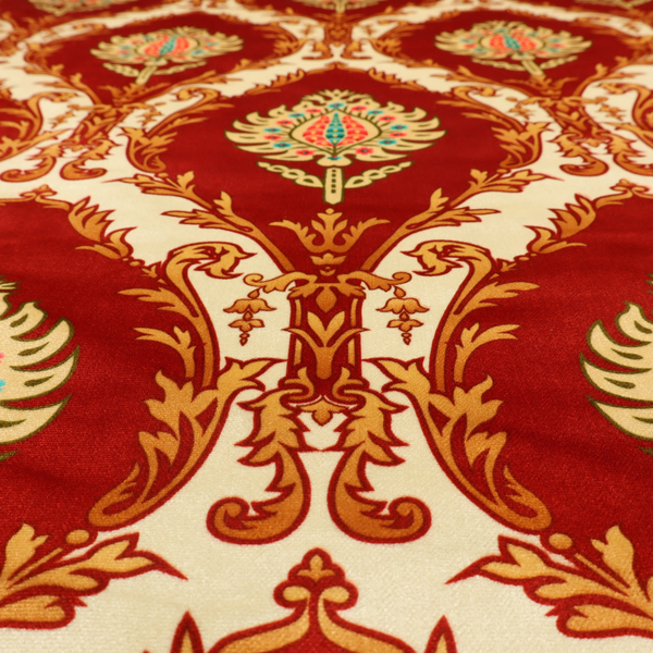 A grand, symmetrical damask-style fabric on a rich crimson red ground featuring ornate cream-colored leaf frames enclosing vibrant, stylized floral pinecones with teal and pink accents.