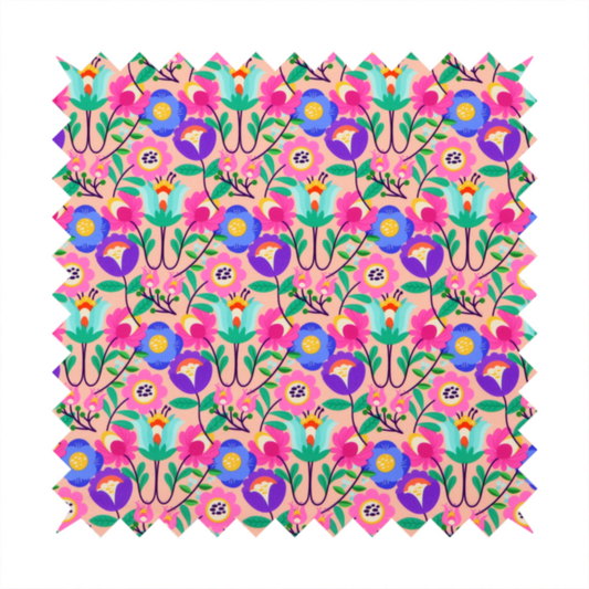 A vibrant and energetic floral fabric on a soft peach-blush background. The design features a symmetrical folk-art arrangement of stylized flowers in neon pink, electric blue, violet, and turquoise, connected by emerald green leaves and delicate black stems in a dense, mirrored repeat.