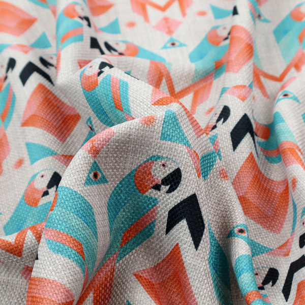 A modern and vibrant geometric fabric on a textured, off-white linen-look background. The design features a symmetrical repeat of abstract parrots rendered in sharp, angular 'prism' shapes of turquoise, coral-pink, and charcoal black. Interspersed between the birds are large coral diamonds and teal triangles, creating a balanced, contemporary tribal-pop aesthetic.