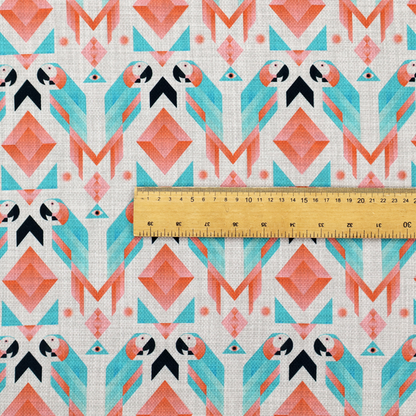 A modern and vibrant geometric fabric on a textured, off-white linen-look background. The design features a symmetrical repeat of abstract parrots rendered in sharp, angular 'prism' shapes of turquoise, coral-pink, and charcoal black. Interspersed between the birds are large coral diamonds and teal triangles, creating a balanced, contemporary tribal-pop aesthetic.