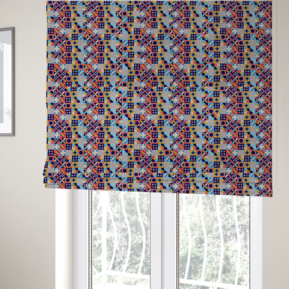 The fabric used to create these Roman blinds is a high-energy, multi-coloured geometric fabric featuring a rhythmic grid of Bauhaus-inspired motifs. The design is a playful mosaic of circles, stars, stripes, and quarter-moons in a vibrant palette of mustard yellow, coral pink, sky blue, and deep midnight navy, all set against a textured, off-white linen-look background.