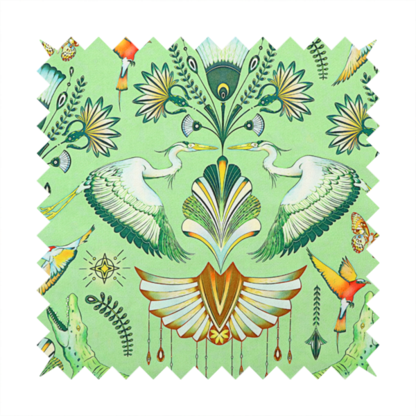 Ornate upholstery fabric with a mirrored botanical and wildlife design. Features white herons with outspread wings, crocodiles, hummingbirds, and butterflies surrounding stylized teal and gold fan motifs on a soft lime-green base.