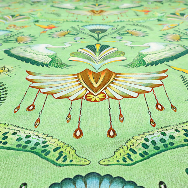 Ornate upholstery fabric with a mirrored botanical and wildlife design. Features white herons with outspread wings, crocodiles, hummingbirds, and butterflies surrounding stylized teal and gold fan motifs on a soft lime-green base.