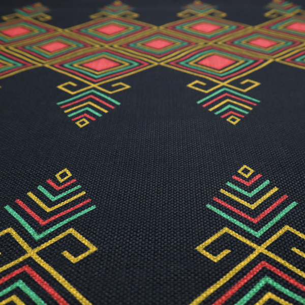 A geometric tribal pattern featuring red, yellow, and green diamonds and linear motifs on a dark charcoal-black fabric background.