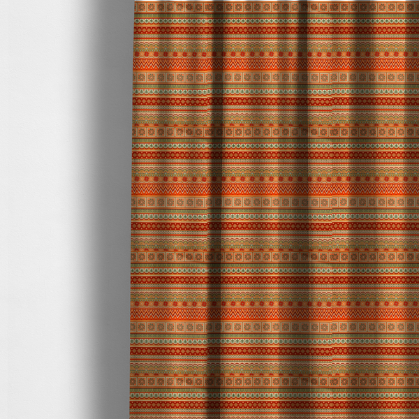 The fabric used to create these made-to-measure curtains is a vibrant, tribal-inspired geometric pattern featuring horizontal bands of zig-zags, floral tiles, and ornamental borders in a warm palette of terracotta, burnt orange, and sage green.