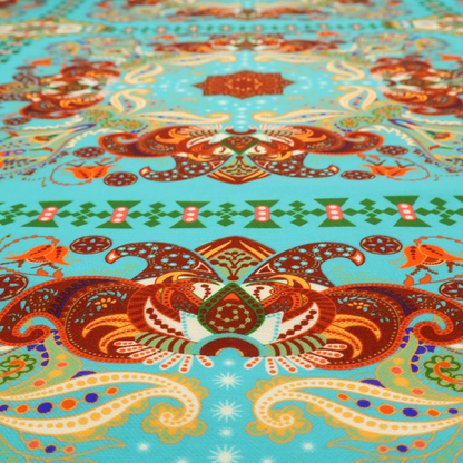 A vibrant and detailed ornamental fabric on a bright turquoise-azure background. The design features a large, symmetrical Persian-style medallion composed of warm terracotta, orange, and gold paisley motifs, framed by vertical geometric borders and diamond-shaped emblems in emerald green and ivory.