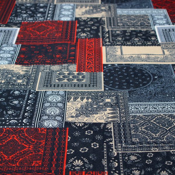 A patchwork-style fabric print featuring a repetitive arrangement of square and rectangular blocks. Each block is filled with intricate navy blue, red, and cream-coloured bandana and paisley motifs, creating a dense, geometric, and traditional textile pattern.